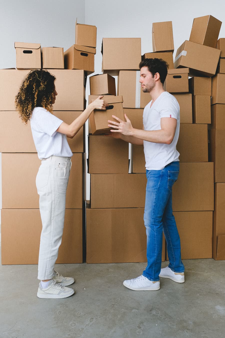 Un couple se passe un carton au milieu d'un déménagement