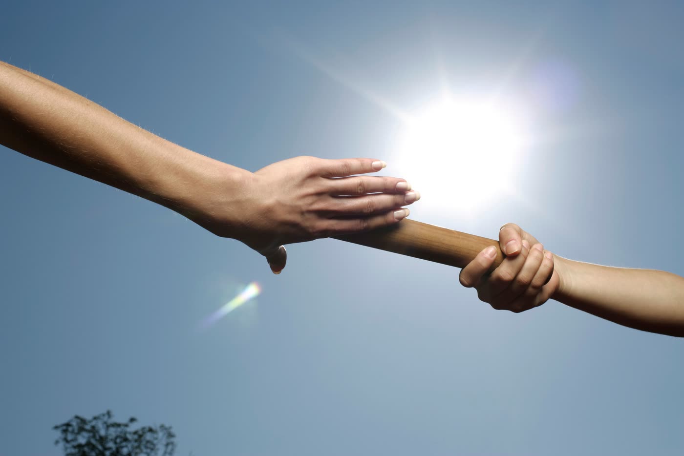 Une main saisit fermement l'avant-bras d'une autre, à contre-jour