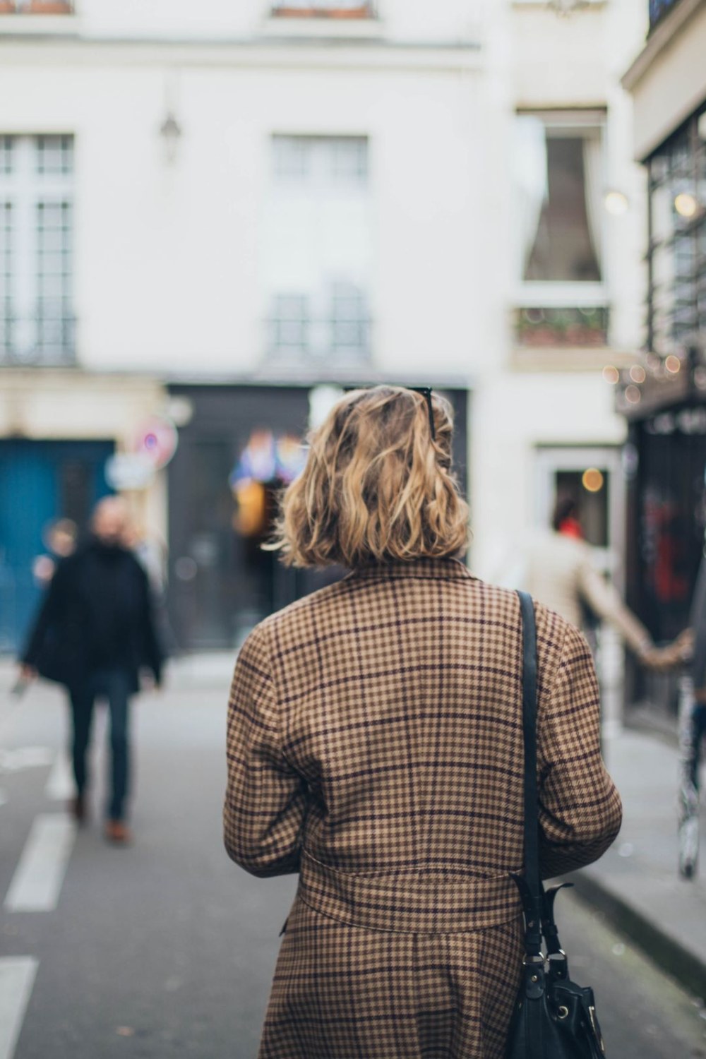 Une femme, de dos, marche dans une rue parisienne