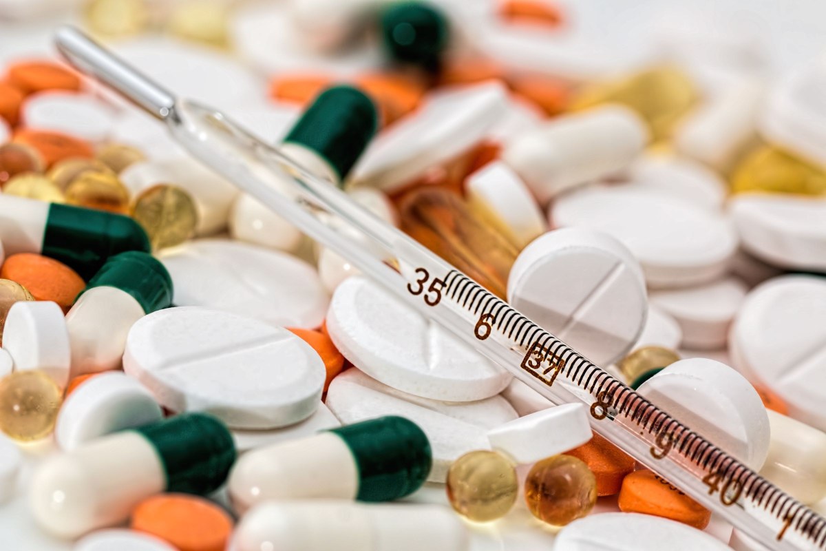 Un thermomètre posé sur des comprimés et des gélules
