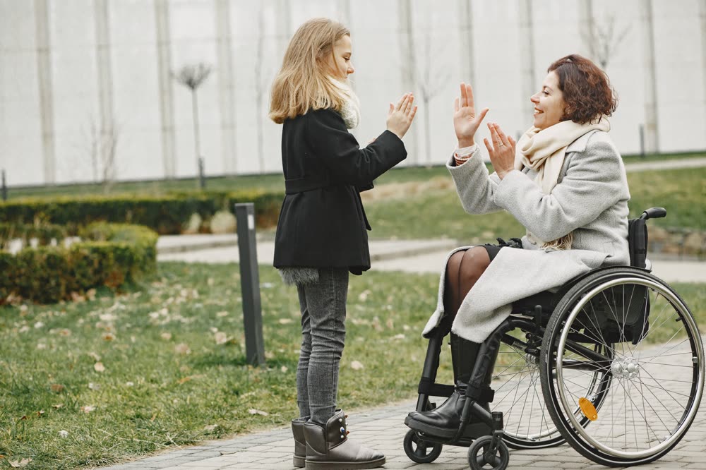 Une femme en fauteuil roulant échange un geste complice avec une accompagnante